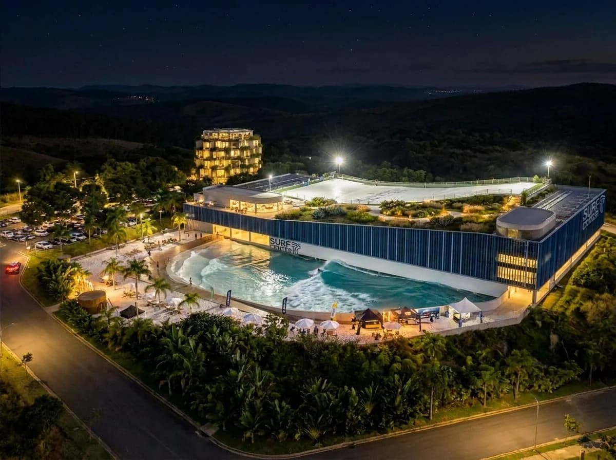 Vista aérea noturna da piscina de ondas do Surf Center Belo Horizonte entre as serras mineiras